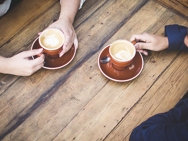 two men in an australian same sex relationship drinking coffee at a wooden table