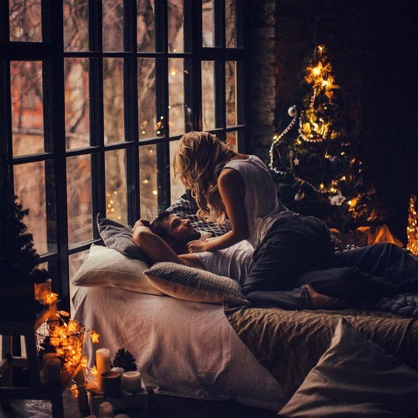 Couple kissing on bed at Christmas
